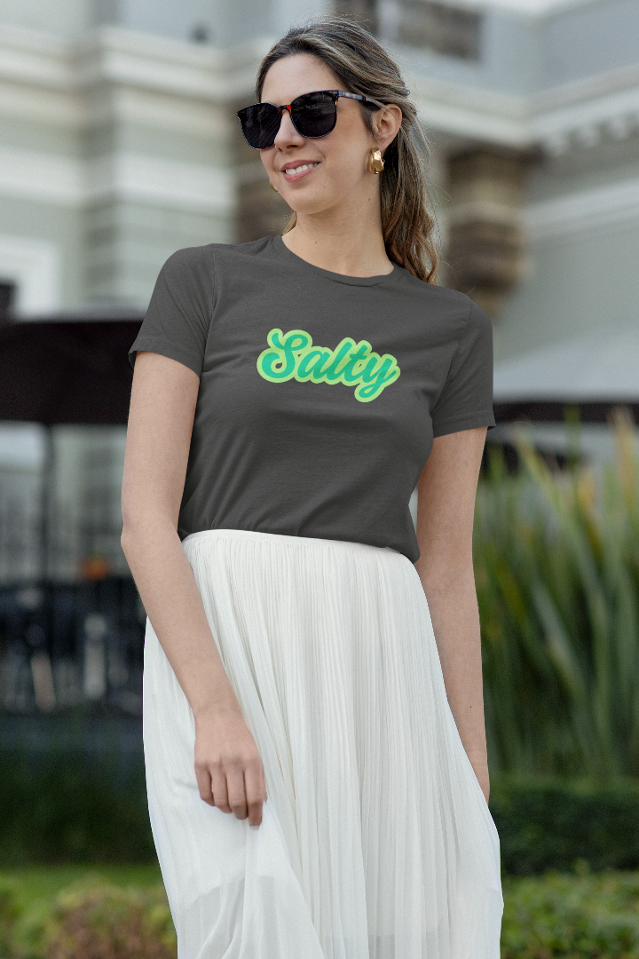 Woman wearing sunglasses, a white skirt and shirt with the word Salty on it. 