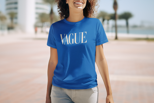 Woman wearing a royal blue graphic t-shirt that says “VAGUE” in white serif letters, smiling outdoors.